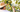 Image of a person in a hat picking pears from a tree with green leaves in an orchard, capturing the harvest process.