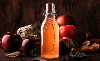 Image promoting "6 Amazing Recipes" for Bourbon Apple Cider, featuring a garnished glass of the drink on a wooden table.